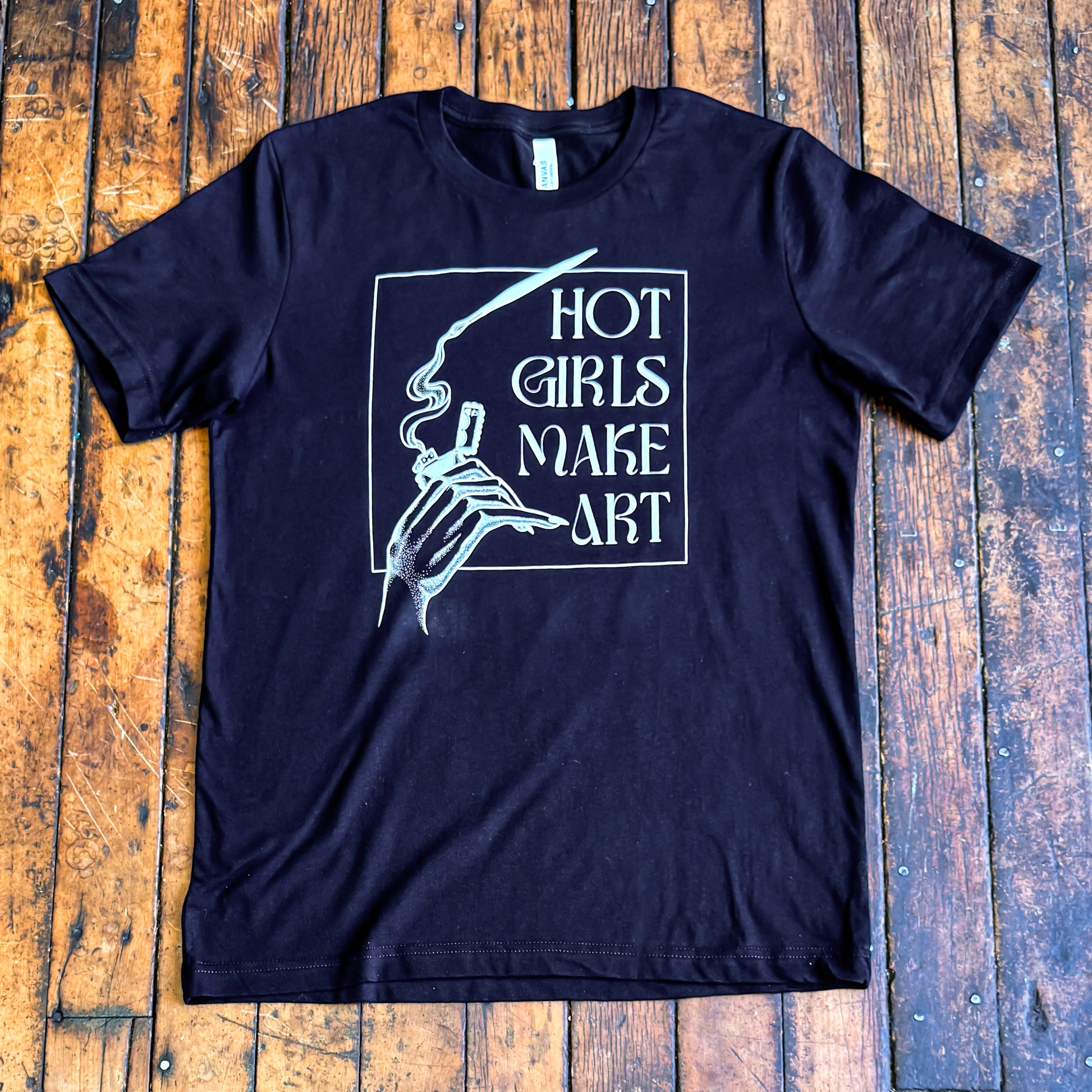 black tee shirt that says hot girls make art on the front with a hand holding a zippo lighter and smoke paint coming out of a paintbrush
