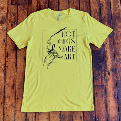 yellow green tee shirt that says hot girls make art on the front with a hand holding a zippo lighter and smoke paint coming out of a paintbrush